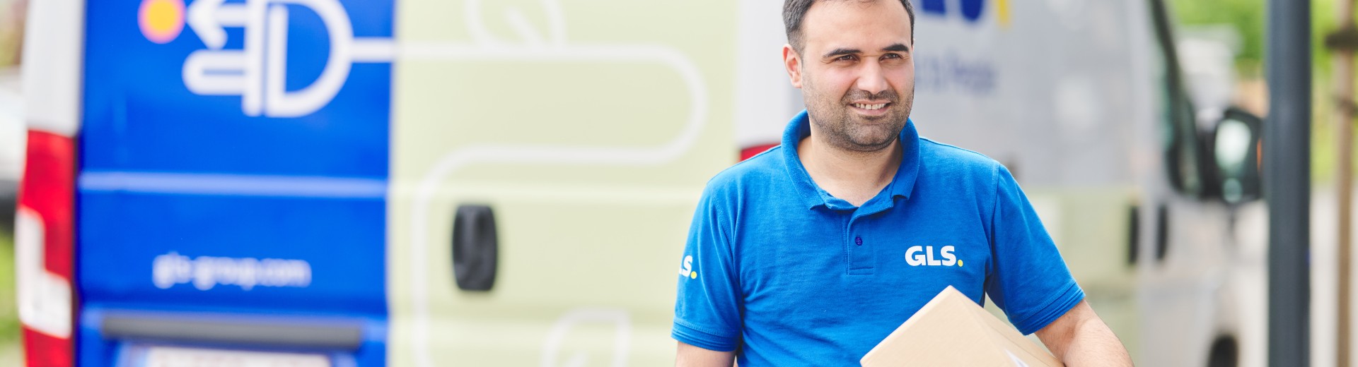 Delivery man holding a parcel in front of his e-van