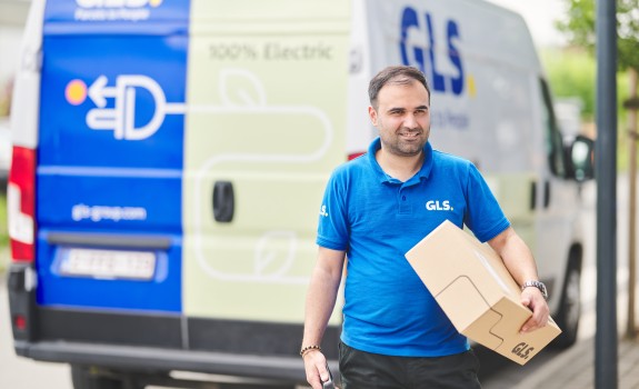 Delivery man holding a parcel in front of his e-van