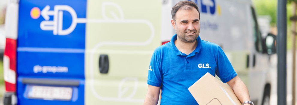 Delivery man holding a parcel in front of his e-van