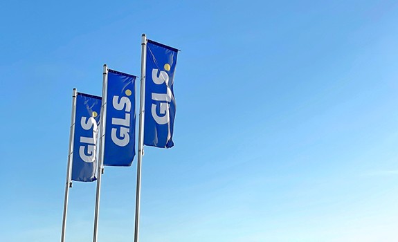 Drapeaux bleus GLS flottant devant un ciel bleu, symbolisant le transport et la logistique de colis en Europe.