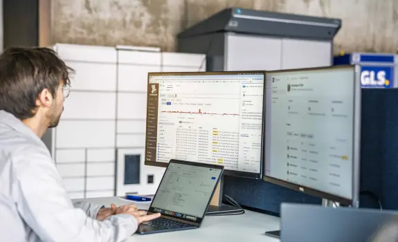 A man working on a computer with lines of code on the screen.